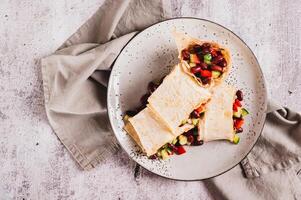 Close up of salad of beans, cucumber and pepper in lavash rolls on a plate on the table top view photo