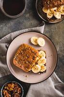 Toast rye bread with chocolate and banana on a plate on the table top and vertical view photo