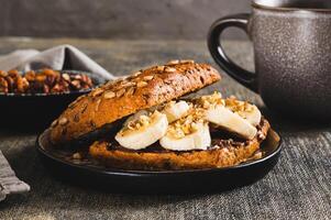 Close up of toast rye bread with chocolate and banana on a plate on the table photo