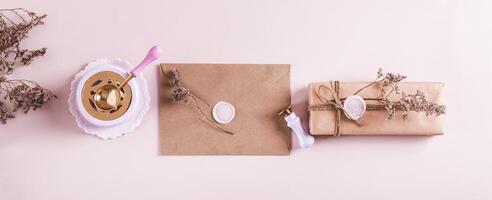 Craft envelope with wax seal and crafting items on pink top view web banner photo
