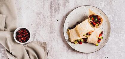 Vegetarian salsa rolls in tortilla on plate on table top view web banner photo