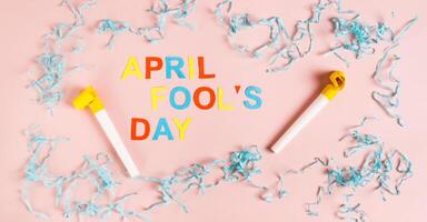 April Fools' Day from colored letters, whistles, balloons and paper on pink top view web banner photo
