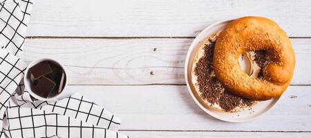 Sweet sandwich with butter, chocolate and sesame seeds on a plate on a table top view web banner photo