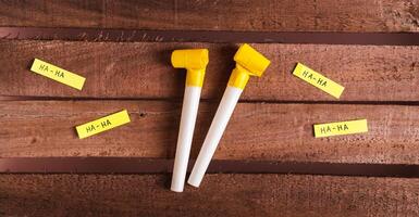 Happy April Fools Day, whistles and funny notes on wooden background top view web banner photo