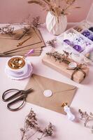 Craft envelope with wax seal and crafting items on pink vertical view photo
