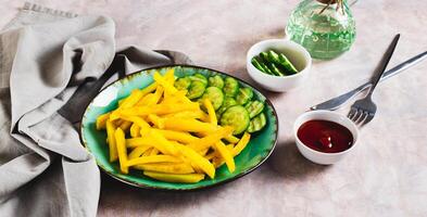 Appetizing French fries and cucumber slices on a plate on the table web banner photo