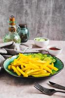 Appetizing French fries and cucumber slices on a plate on the table vertical view photo