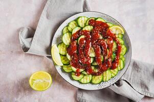 Close up of mexican spicy cucumbers with chili sauce and lime on a plate on the table top view photo