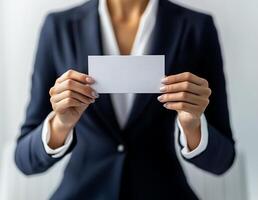 Business professional holds a blank card while dressed in formal attire in a modern office setting photo
