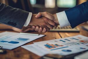 Business professionals engage in a handshake while discussing financial reports in a modern office setting near midday photo