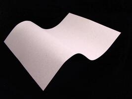 Wavy paper sheet over black background for different design purposes photo