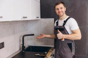 Plumber showing running water from tap after successful installation in kitchen photo