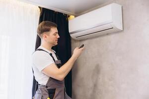 Technician using a remote control to control a wall mounted air conditioner photo