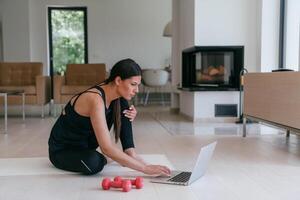 Young Beautiful Female Exercising, Stretching and Practising Yoga with Trainer via Call Conference in Bright Sunny House. Healthy Lifestyle, Wellbeing and Mindfulness Concept. photo