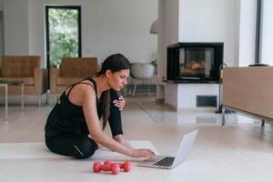 Young Beautiful Female Exercising, Stretching and Practising Yoga with Trainer via Call Conference in Bright Sunny House. Healthy Lifestyle, Wellbeing and Mindfulness Concept. photo