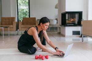 Young Beautiful Female Exercising, Stretching and Practising Yoga with Trainer via Call Conference in Bright Sunny House. Healthy Lifestyle, Wellbeing and Mindfulness Concept. photo