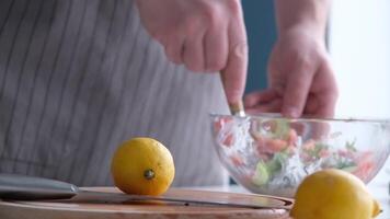 man making Greek salad in the kitchen, adding lemon video
