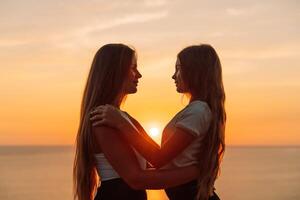 Mother daughter sunset. Mother and daughter stand on the beach, hugging and looking at each other enjoying the sunset. photo