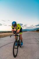 Triathlete riding his bicycle during sunset, preparing for a marathon. The warm colors of the sky provide a beautiful backdrop for his determined and focused effort. photo