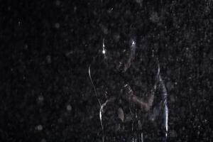 A triathlete braving the rain as he cycles through the night, preparing himself for the upcoming marathon. The blurred raindrops in the foreground and the dark, moody atmosphere in the background add photo