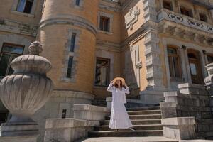 A woman in a white dress is standing on a set of stairs in front of a building photo