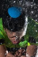 A triathlete braving the rain as he cycles through the night, preparing himself for the upcoming marathon. The blurred raindrops in the foreground and the dark, moody atmosphere in the background add photo