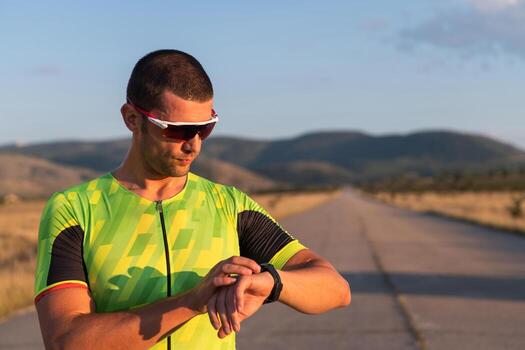 The triathlete checking his training statistics on a smartwatch, analyzing his performance and progress. With dedication, discipline, and perseverance, he strives to improve his physical abilities and photo