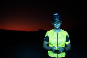 A triathlete using a smartphone while taking a break from a hard night's cycling training photo