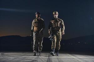 Two professional soldiers marching through the dark of night on a dangerous mission, epitomizing their unwavering bravery, unwavering teamwork, and the high-stakes intensity of their specialized photo