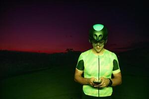 A triathlete using a smartphone while taking a break from a hard night's cycling training photo