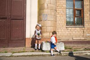 children's in school uniforms with a briefcase walk and eat near the school photo