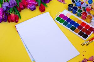 layout with aquarelle palette, paint brushes on yellow background photo
