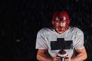 American Football Field. Lonely Athlete Warrior Standing on a Field Holds his Helmet and Ready to Play. Player Preparing to Run, Attack and Score Touchdown. photo