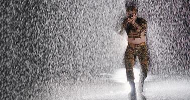 Army soldier in Combat Uniforms with an assault rifle, plate carrier and combat helmet going on a dangerous mission on a rainy night. photo