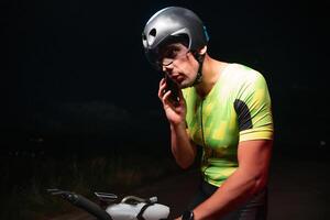 A triathlete using a smartphone while taking a break from a hard night's cycling training photo