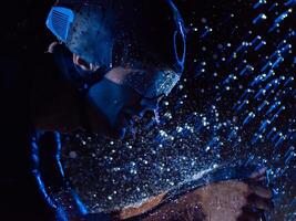 A triathlete braving the rain as he cycles through the night, preparing himself for the upcoming marathon. The blurred raindrops in the foreground and the dark, moody atmosphere in the background add photo