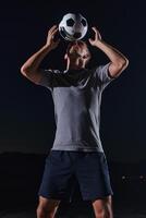 Portrait of a young handsome soccer player man on a street playing with a football ball photo