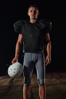 American Football Field. Lonely Athlete Warrior Standing on a Field Holds his Helmet and Ready to Play. Player Preparing to Run, Attack and Score Touchdown. photo