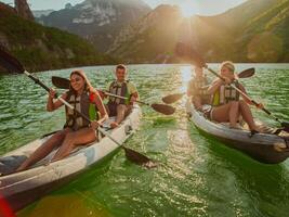 A group of friends enjoying fun and kayaking exploring the calm river, surrounding forest and large natural river canyons during an idyllic sunset. photo