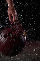 Close up of American Football Athlete Warrior Standing on a Field focus on his Helmet and Ready to Play. Player Preparing to Run, Attack and Score Touchdown. Rainy Night with Dramatic lens flare photo