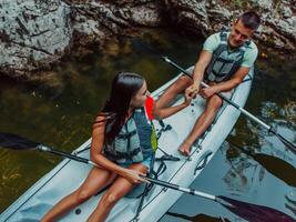A young couple enjoying an idyllic kayak ride in the middle of a beautiful river surrounded by forest greenery photo