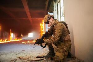 Soldier in action near window changing magazine and take cover photo