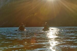 A group of friends enjoying fun and kayaking exploring the calm river, surrounding forest and large natural river canyons during an idyllic sunset. photo