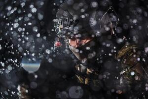 Army soldier in Combat Uniforms with an assault rifle, plate carrier and combat helmet going on a dangerous mission on a rainy night. photo