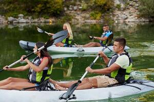 A group of friends enjoying having fun and kayaking while exploring the calm river, surrounding forest and large natural river canyons photo