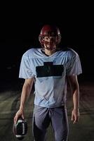 American Football Field. Lonely Athlete Warrior Standing on a Field Holds his Helmet and Ready to Play. Player Preparing to Run, Attack and Score Touchdown. photo
