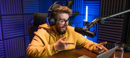 Banner man recording podcast in studio copy space. Confident man with headphones and microphone recording a podcast. Happy guy talking on web radio. photo