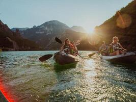 A group of friends enjoying fun and kayaking exploring the calm river, surrounding forest and large natural river canyons during an idyllic sunset. photo