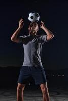 Portrait of a young handsome soccer player man on a street playing with a football ball photo