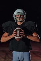 American Football Field. Lonely Athlete Warrior Standing on a Field Holds his Helmet and Ready to Play. Player Preparing to Run, Attack and Score Touchdown. photo